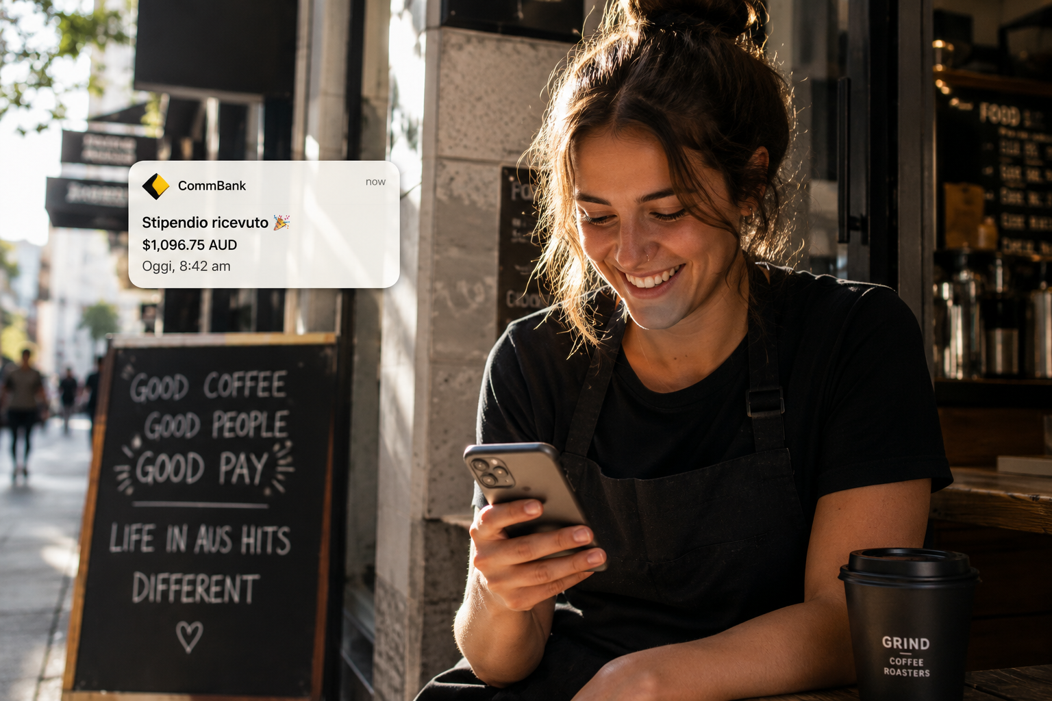 Barista sorridente legge sul telefono la notifica della banca con lo stipendio ricevuto in dollari australiani
